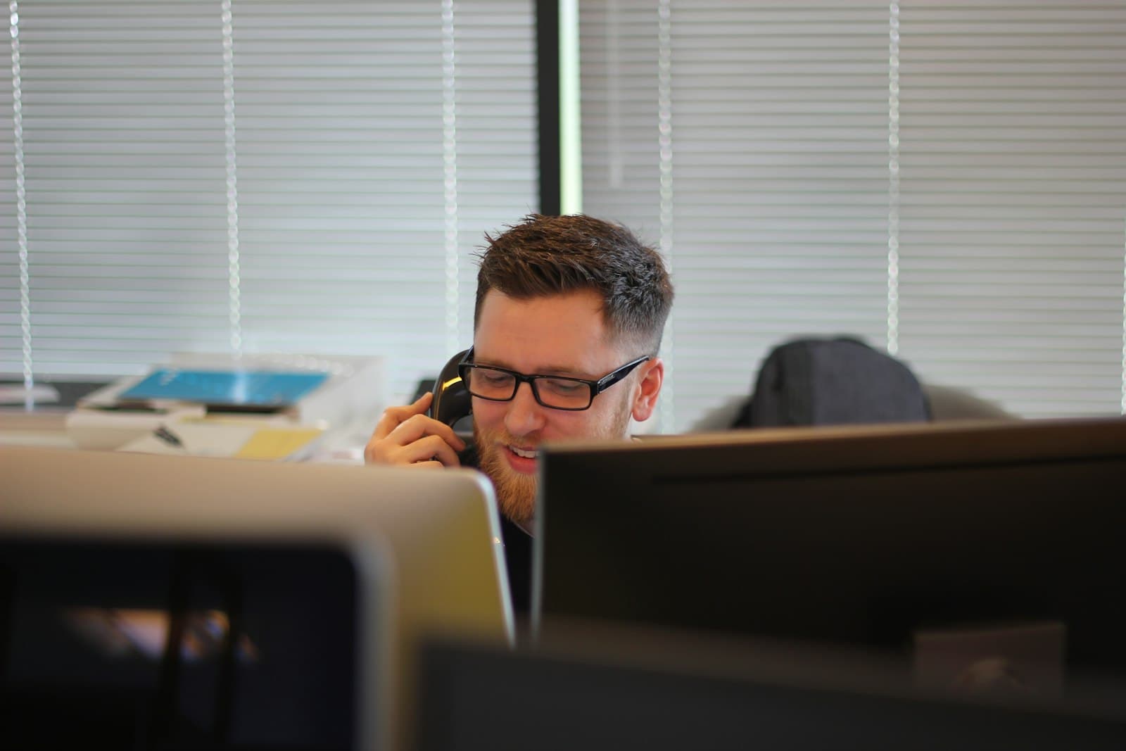 A man taking a call on a desk phone
