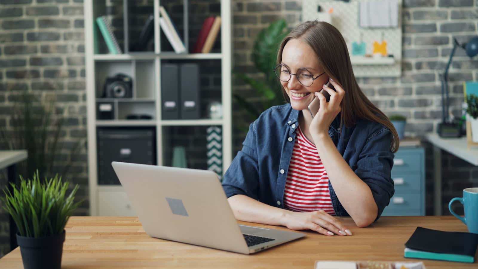 A business owner taking a phone call while working on a laptop